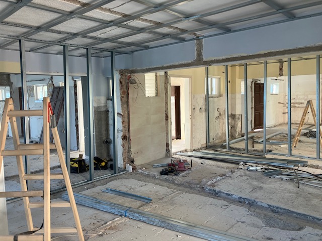 Wide view of partition framing and ceiling grid across several emerging rooms.