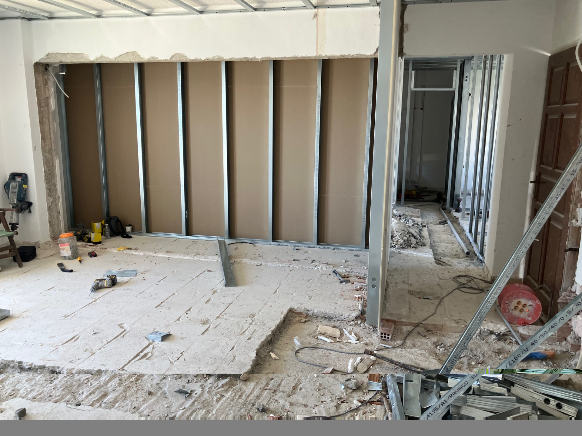 Wide unfinished room with metal-stud partitions defining the emerging internal layout.