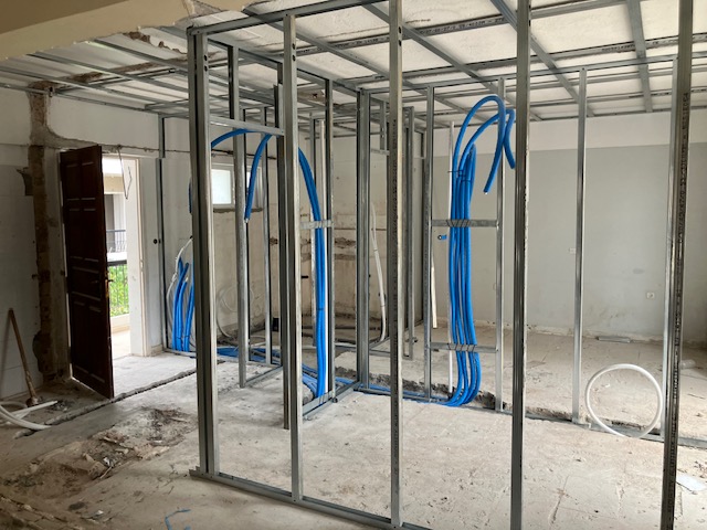 First-floor interior with plasterboard partition framework and blue building-services pipework in place.
