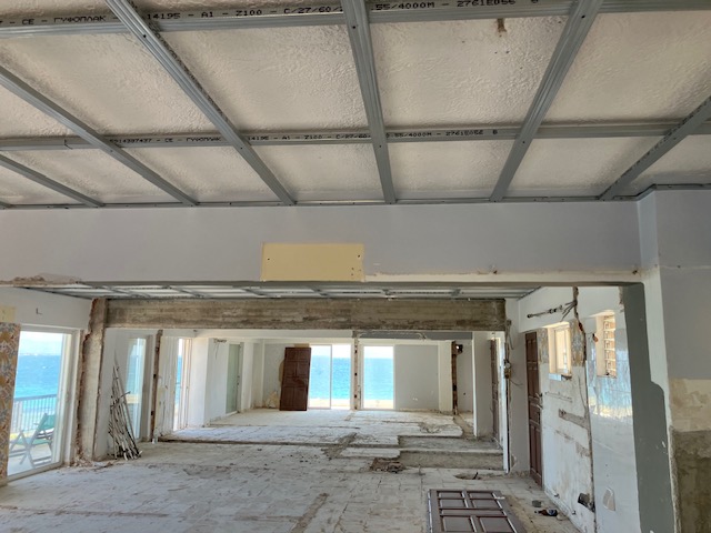 Long interior sightline through the residence towards the sea, with ceiling framework installed.