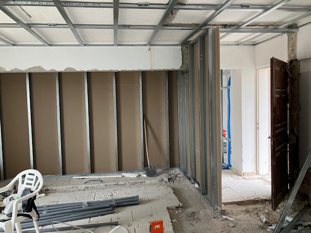 First-floor room with partition and ceiling framing progressing around the internal layout.