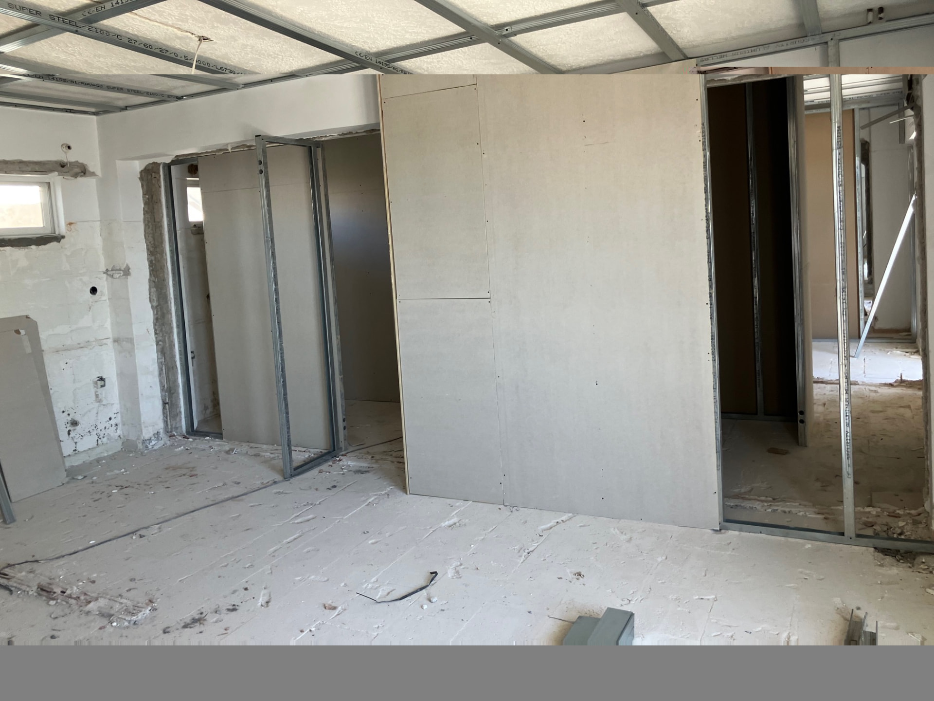 Broad unfinished interior showing drywall partitions and suspended ceiling framework.